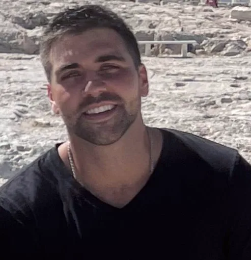 Paul smiling, seated outdoors in a black t-shirt