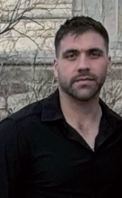 Paul Rammeloo in a black shirt, standing against a stone wall